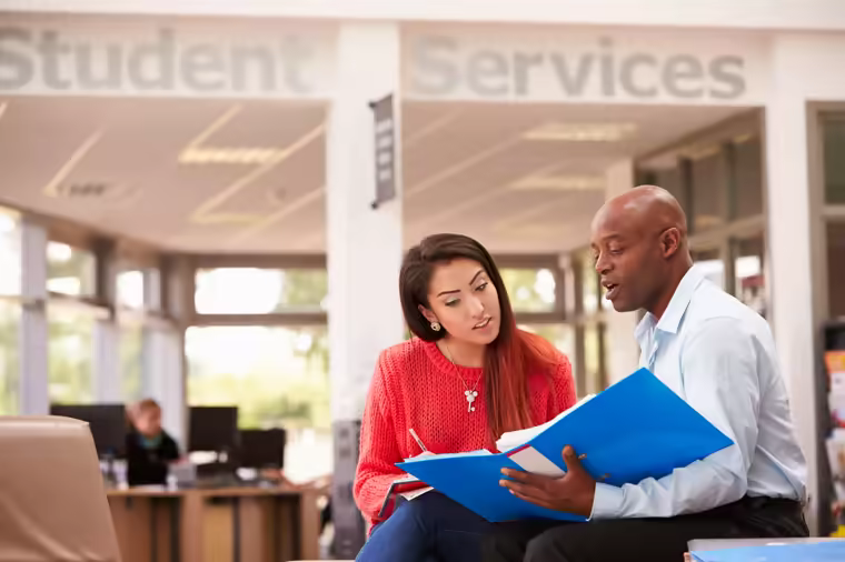 A student and a careers adviser going through a folder together in Student Services.